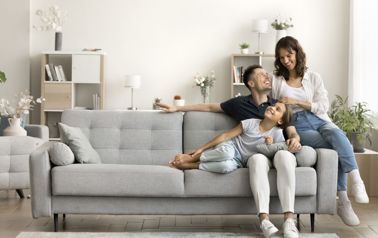Mother, father, and young daughter sitting close together on a couch