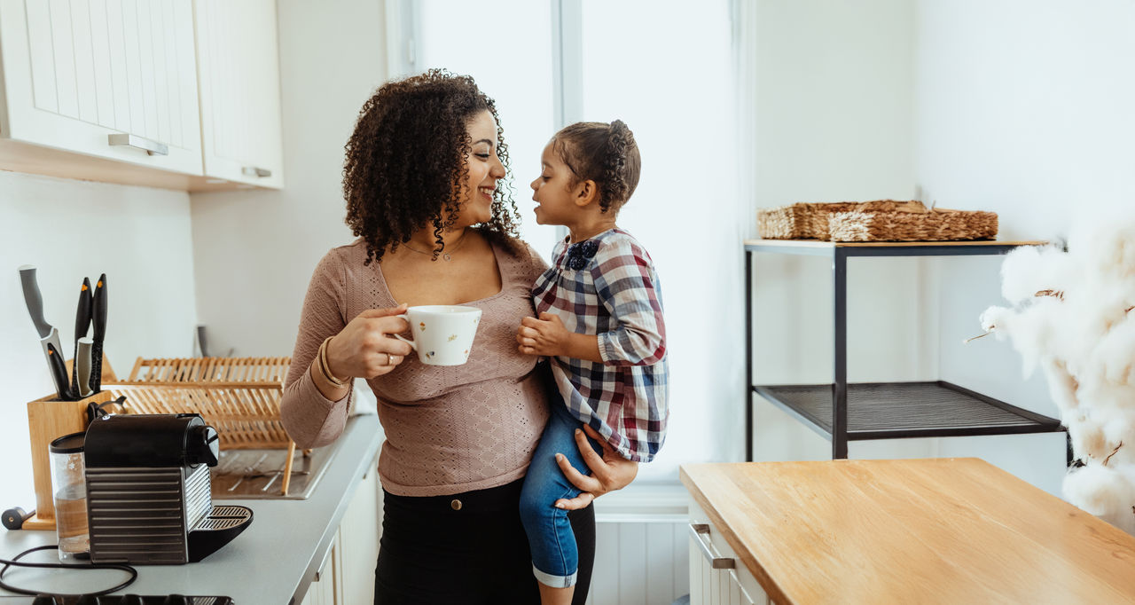 Mom holding daughter with coffee mug