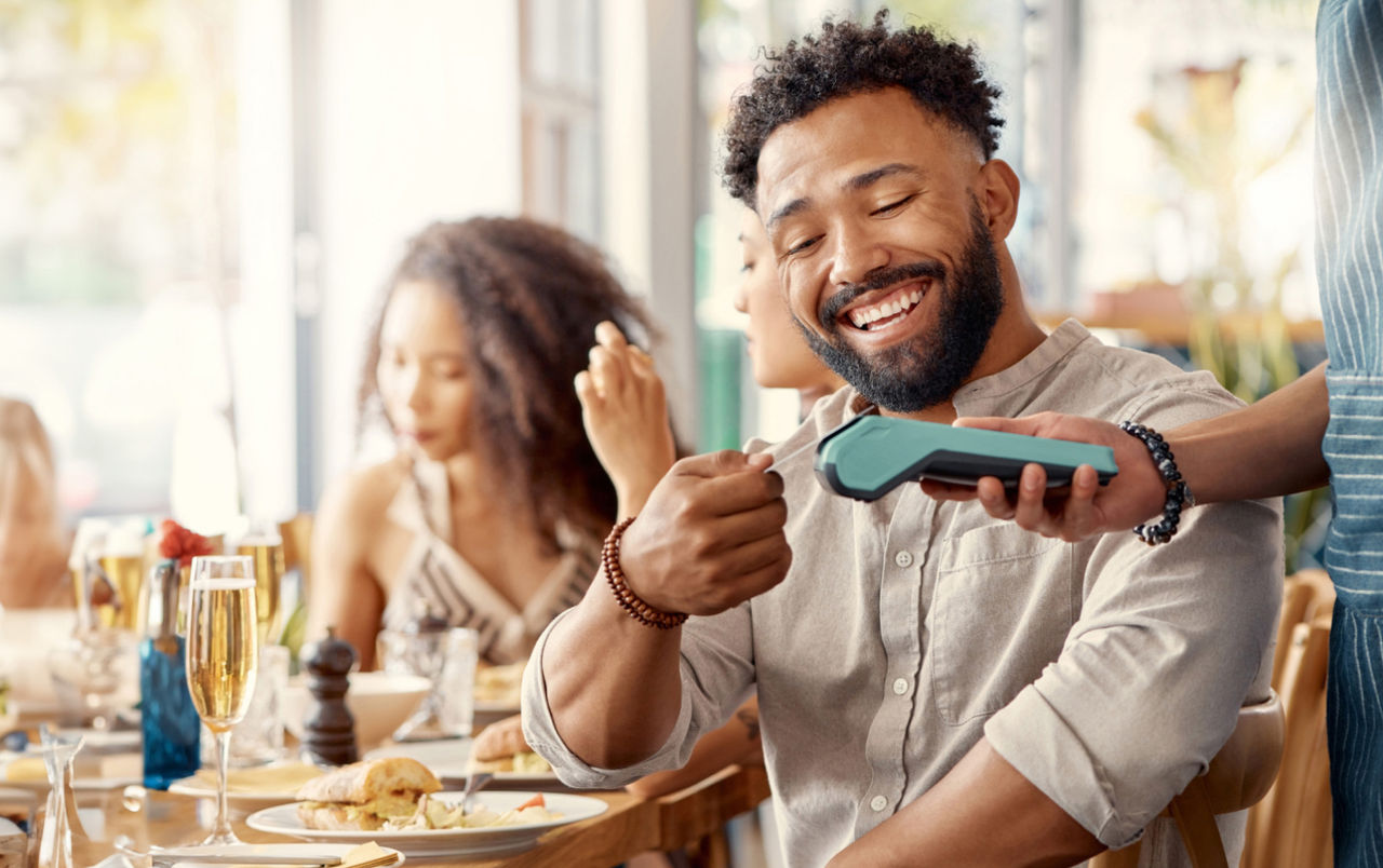 Man sitting in a restaurant and paying his bill with his credit card