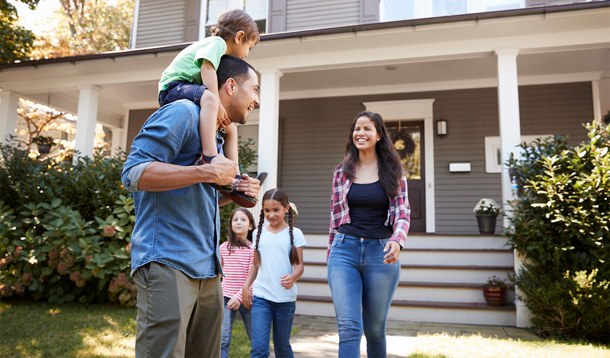 Parents and their three children standing outside of their home