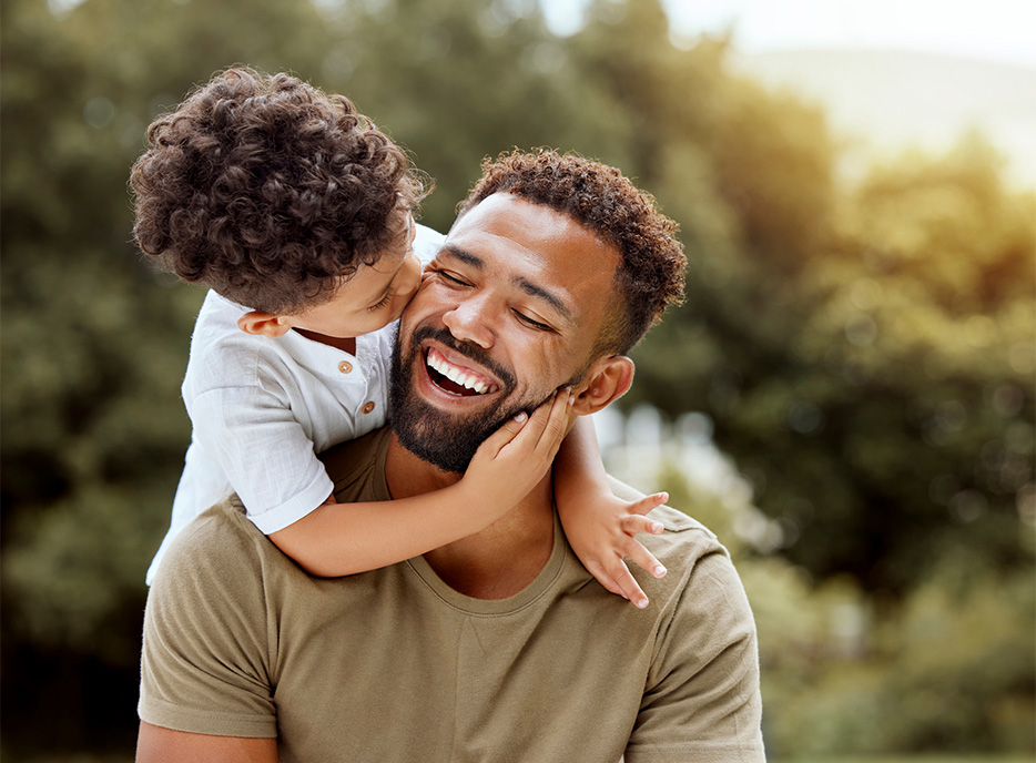 Father with his young son on his back and kissing his cheek