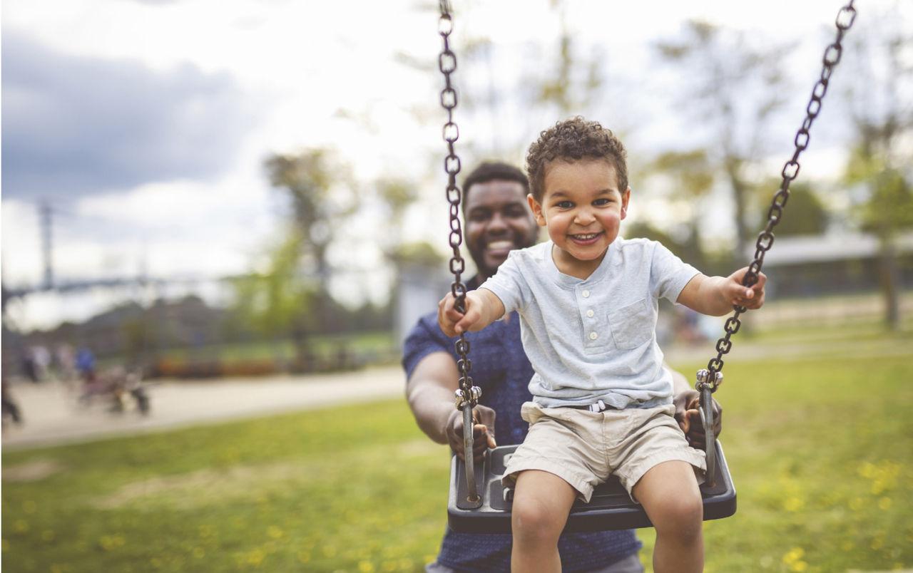 Father pushing his young son on a swing