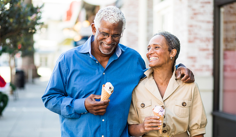 Retired couple walking down a sidewalk while eating ice cream cones