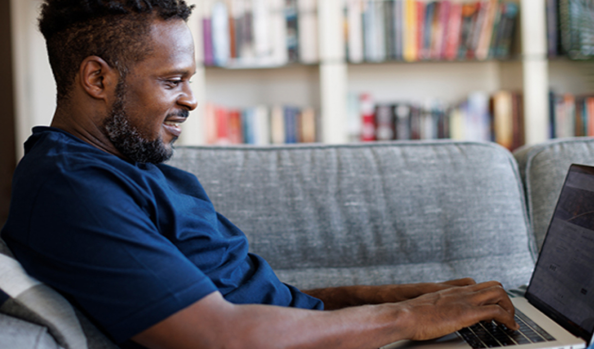 Man sitting on a couch using his laptop