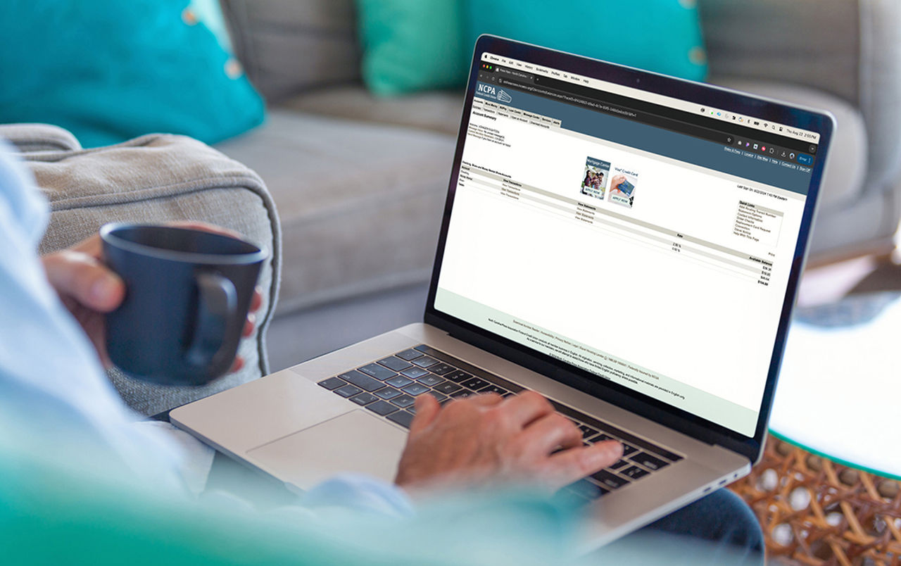 Laptop sitting on a man's lap displaying his accounts at NCPAFCU